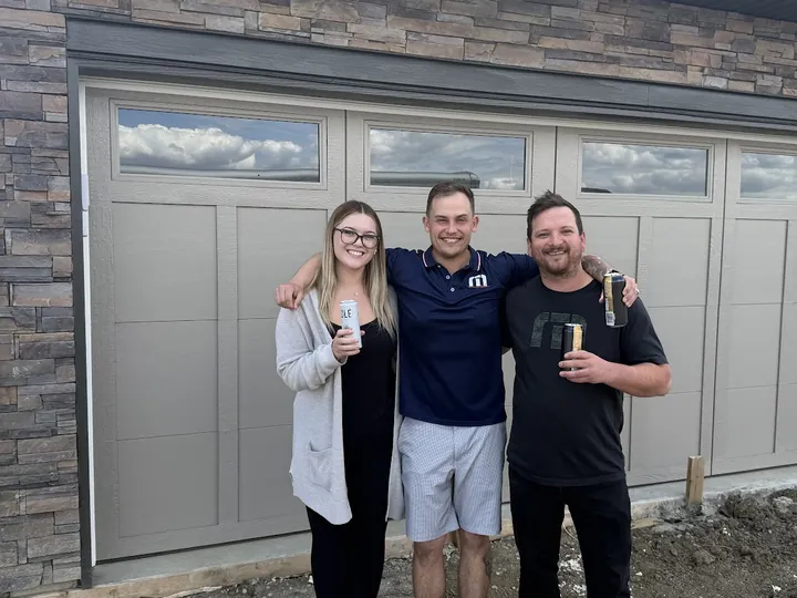 Mackenzie M. and her partner with Cameron in front of their new garage